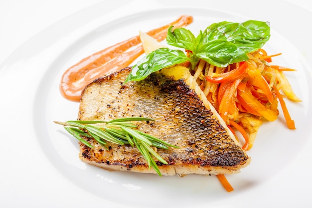 Dish of fish fillet with basil and lemon on plate isolated on white