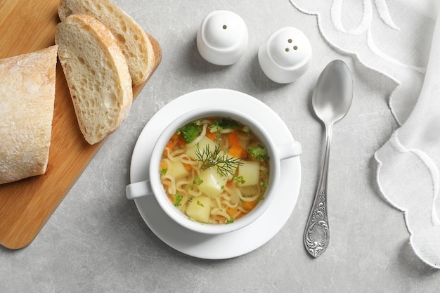 Dish of fresh homemade vegetable soup served on light grey table flat lay