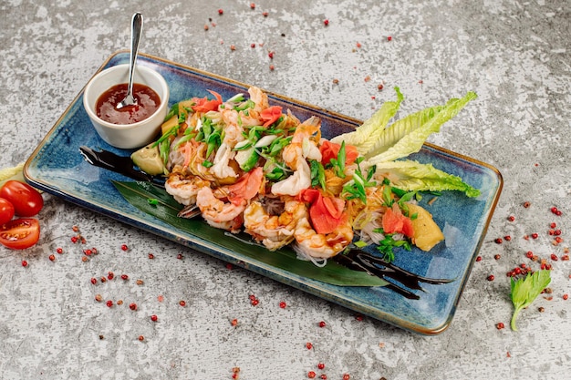 Dish of glass noodles with srimps and vegetables on grey background Wok menu