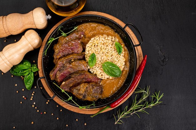 Dish of grilled meat sauce and rice on wooden background
