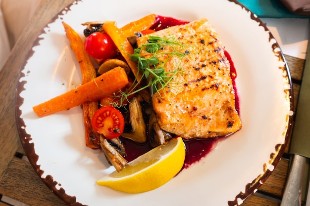 A dish of grilled salmon fillet with vegetables on a plate.