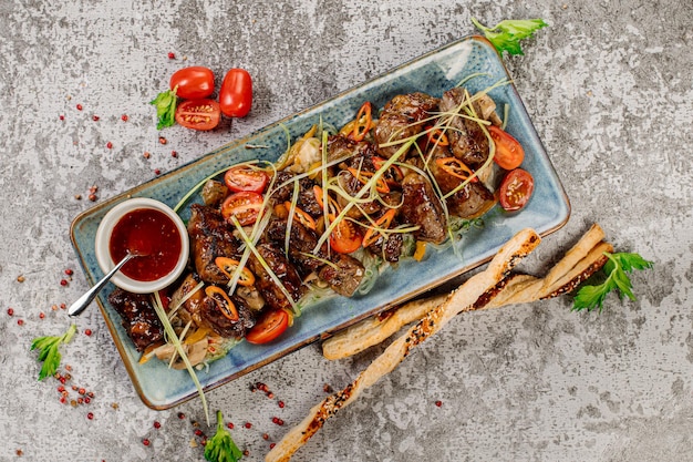 Photo dish of grilled veal meat pieces with sauce and vegetables