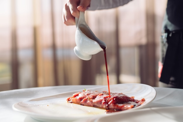 The Dish Is Carpaccio. The waiter pours the sauce over the dish Carpaccio.