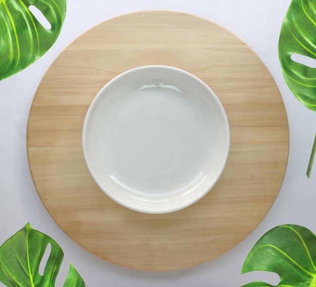 Dish is placed on a round wooden table with monstera palm leaves for decoration
