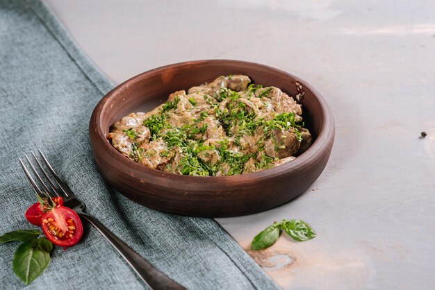 Dish of liver with herbs on the wooden background