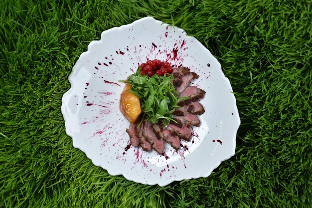 Dish salad with duck breast, pineapple and lettuce in a white plate