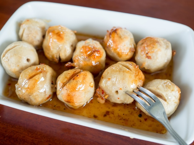 Dish of Thai meatballs on spicy and sweet sauce.