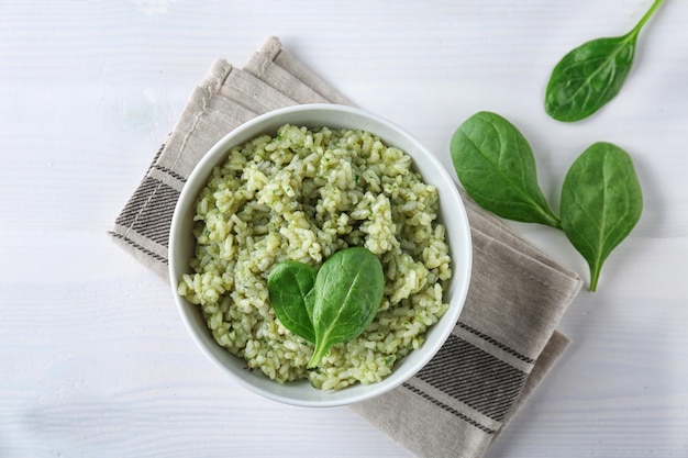 Dish with delicious spinach risotto on wooden table