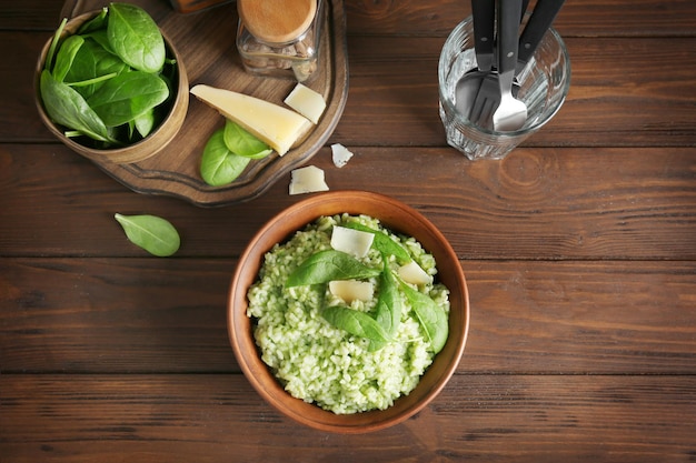 Dish with delicious spinach risotto on wooden table