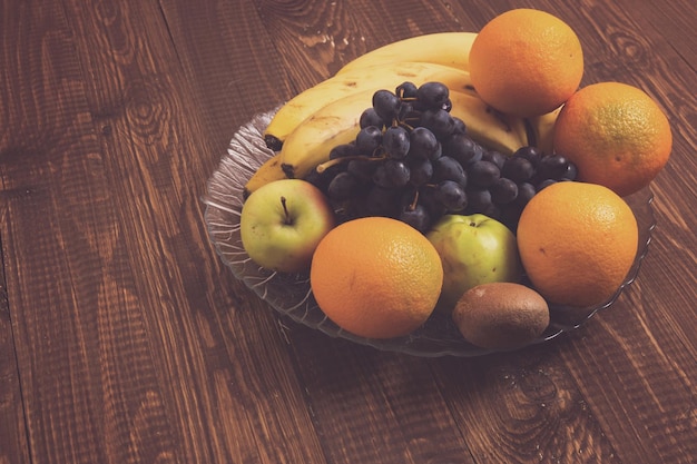 A dish with different fruit is on the wood table