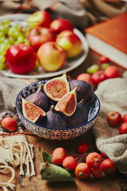 Dish with figs apples and grapes with warm cozy knitwear autumn leaves and apples