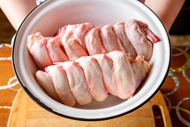 Dish with fresh raw wings in female hands