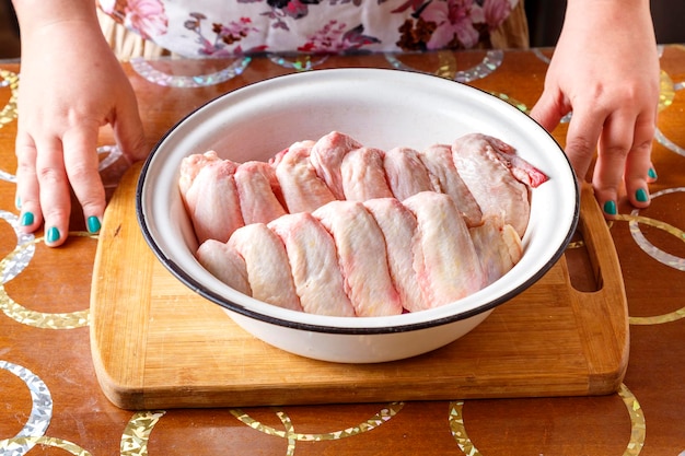 Dish with fresh raw wings in female hands