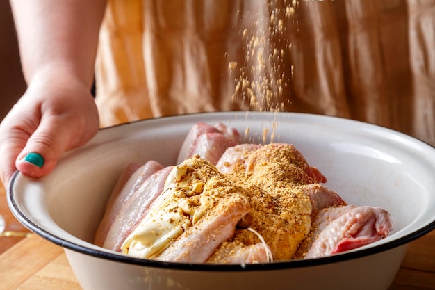 A dish with fresh raw wings on a wooden table spices pour into it