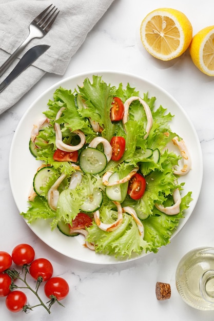 Dish with Gourmet fried squid rings Vegetable fresh green salad white plate Top view Seafood concept