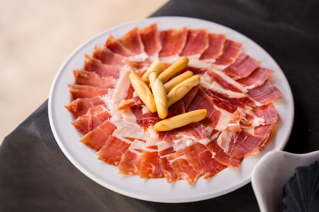 Dish with Iberico ham cut ready to eat Ham cutter man Service of a person cutting a piece of ham traditional food of spain