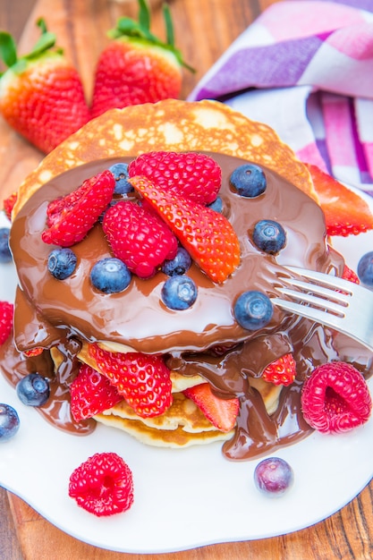 Dish with pancakes and strawberry,raspberry and blueberry and chocolate