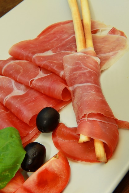 dish with raw ham and breadstick