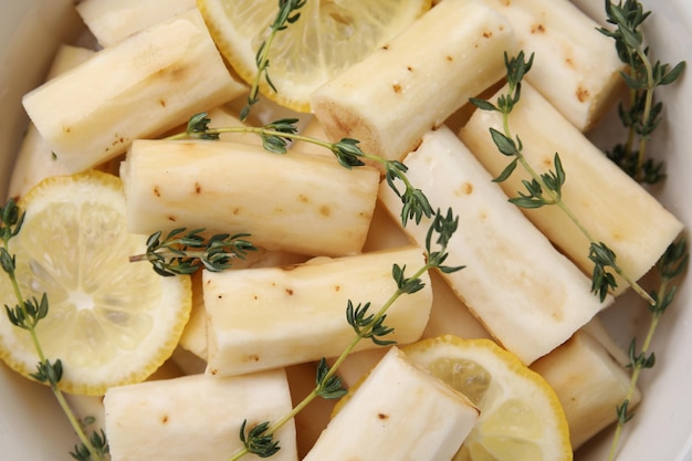 Dish with raw salsify roots lemon and thyme top view