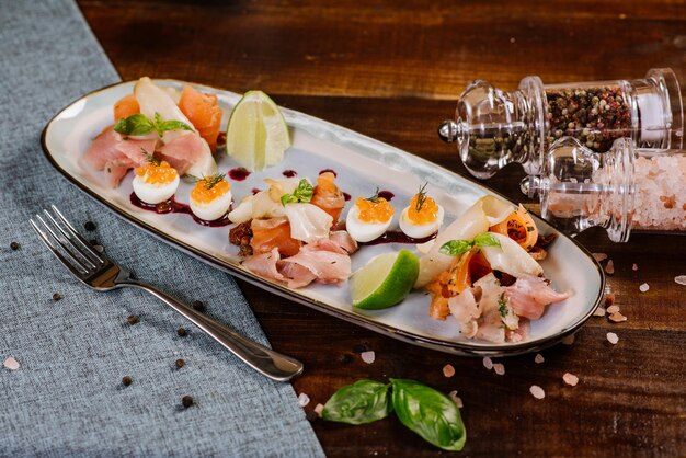 A dish with red, white fish, caviar and vegetables on the wooden background