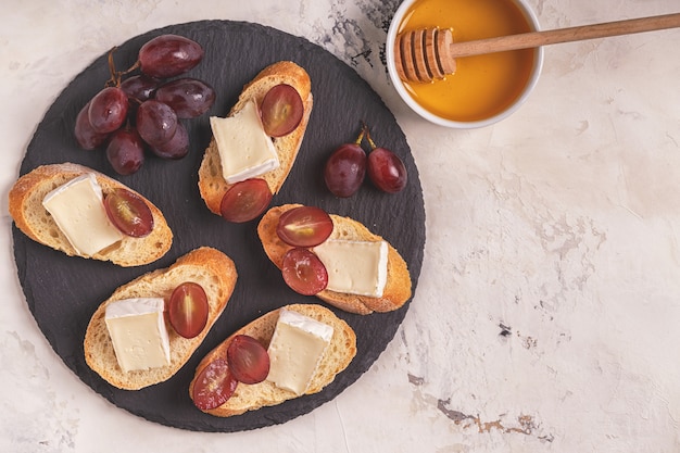 Dish with sandwiches of cheese, grapes and honey