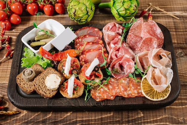 A dish with variety of smoked meat, salamy, ham on wooden background