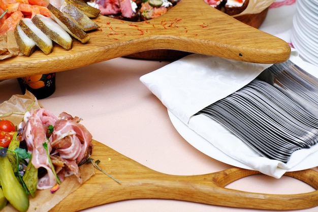 Dishes on the buffet table Meat vegetable and fish snacks on wooden trays Nearby are cutlery in napkins