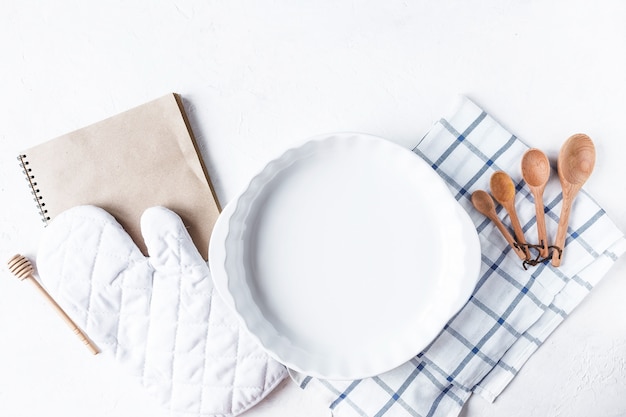 Piatti e accessori da cucina per la cottura sul tavolo della cucina su uno sfondo bianco