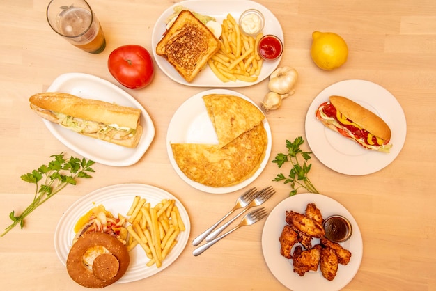 Dishes and snacks of a restaurant seen from the top Chicken wings puppy burger potato omelette chicken sandwich