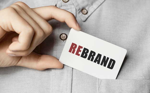 A disheveled business man holds up a cardboard sign with the words Rebranding