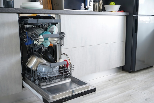 Photo dishwasher machine, open and loaded with dishes in the kitchen