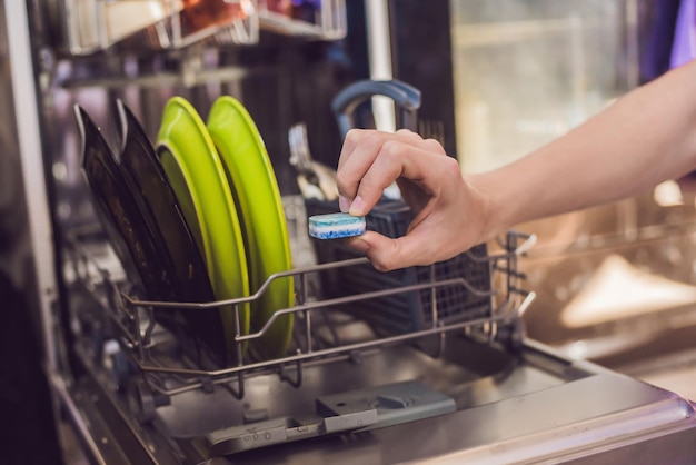 写真 汚れた食器を備えた食器洗い機粉末食器洗いタブレットとすすぎ補助キッチンで食器を洗う