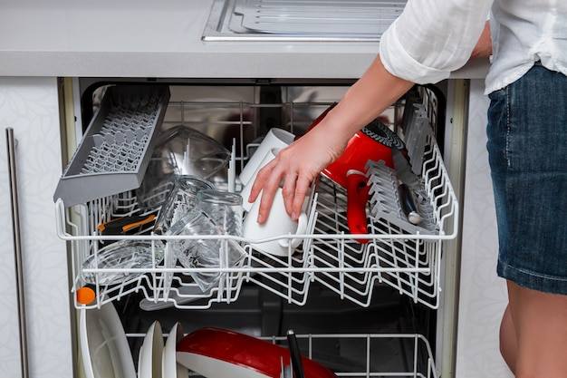dishwasher with an open door and extended basket shelves with dishes and a woman in a short skirt grabbing a cup