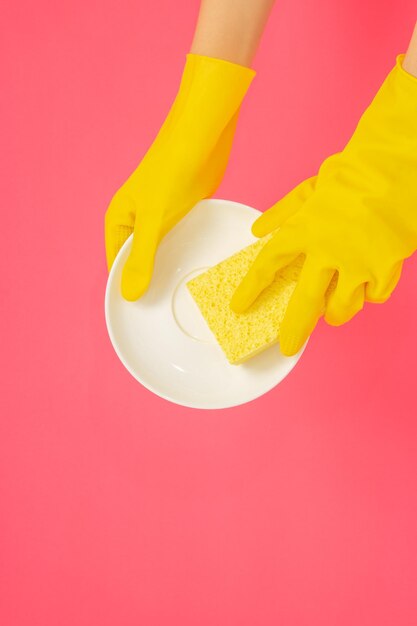 写真 食器洗いのコンセプト ゴム手袋をはめて黄色いスポンジを持ち、食器を洗う