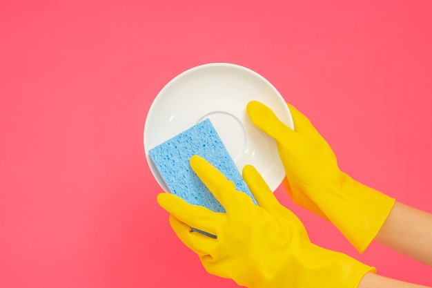 Dishwashing concept hands in rubber gloves to holding light\
blue sponge and wash the dishes