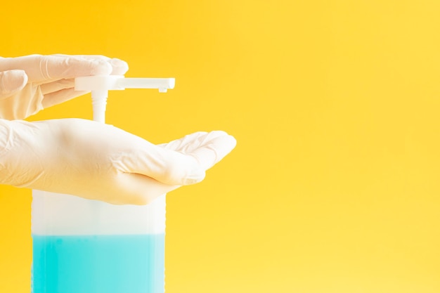 Disinfectant and latex gloves on a yellow background.