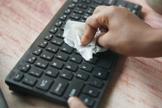 disinfecting keyboard with a white tissue on table