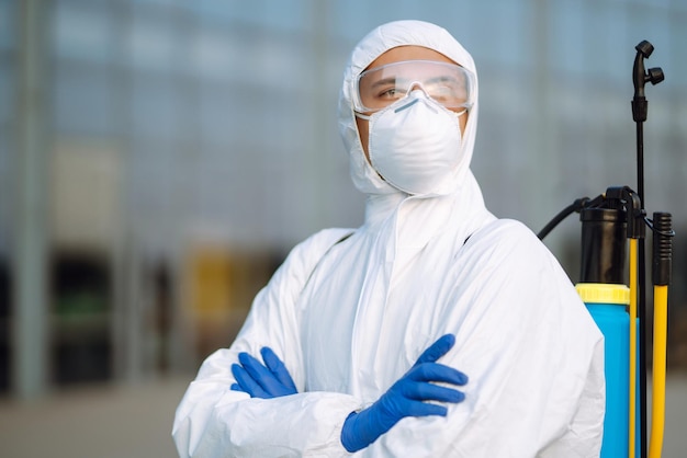 Disinfecting to prevent COVID-19, Man in protective hazmat suit with with spray.