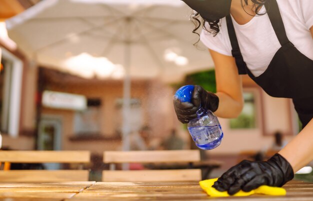 Disinfecting to prevent COVID-19. Waitress cleaning the table.