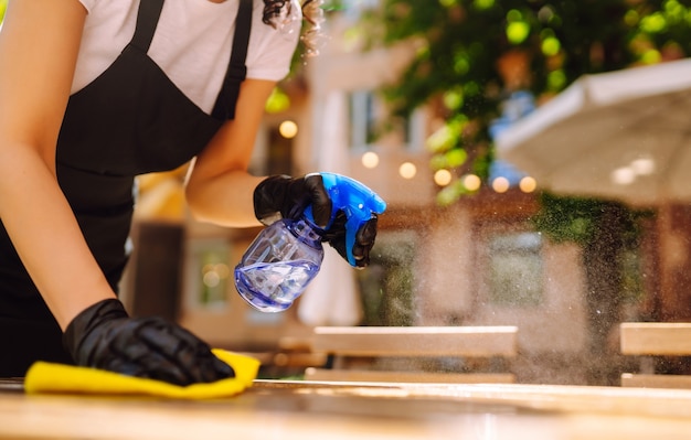 Disinfecting to prevent COVID-19. Waitress cleaning the table.