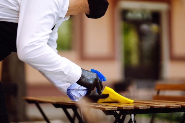 Foto disinfezione per prevenire il covid19 cameriere che pulisce il tavolo con spray disinfettante