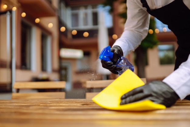 Disinfecting to prevent COVID19 Waiter cleaning the table with Disinfectant Spray