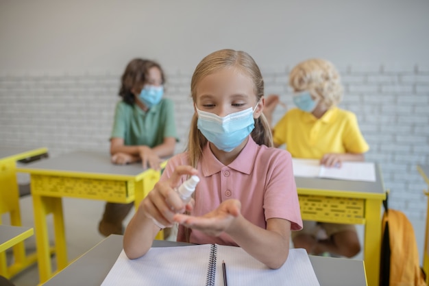 Disinfection. Fair-haired girl in a mask spraying sanitizer on her hands