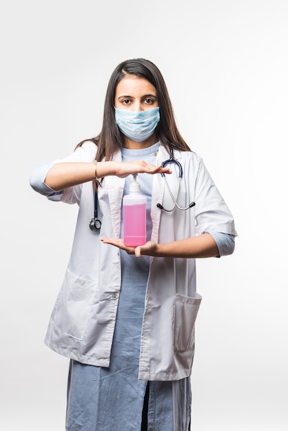 Disinfezione e lavaggio delle mani - la dottoressa indiana in uniforme e maschera facciale mette un disinfettante o un disinfettante sulle mani. protezione contro il coronavirus covid-19