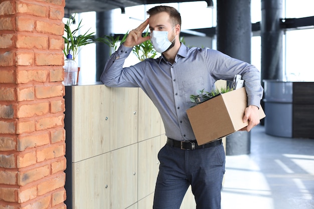 Dismissal employee in an epidemic coronavirus covid-19. Dismissed worker going from the office with his office supplies