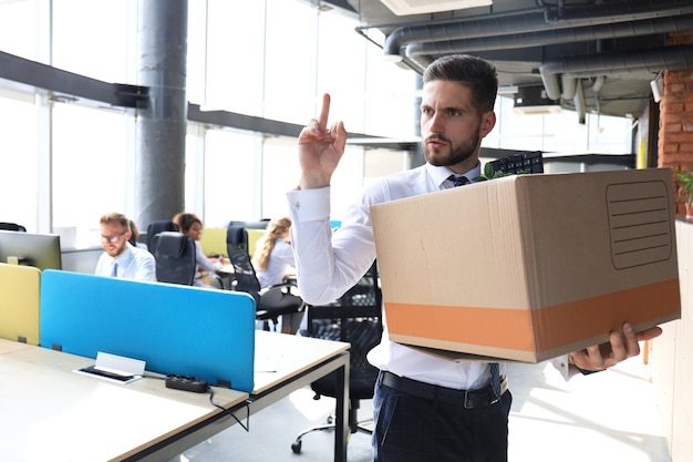 Dismissed worker going from the office with his office supplies showing fuck.