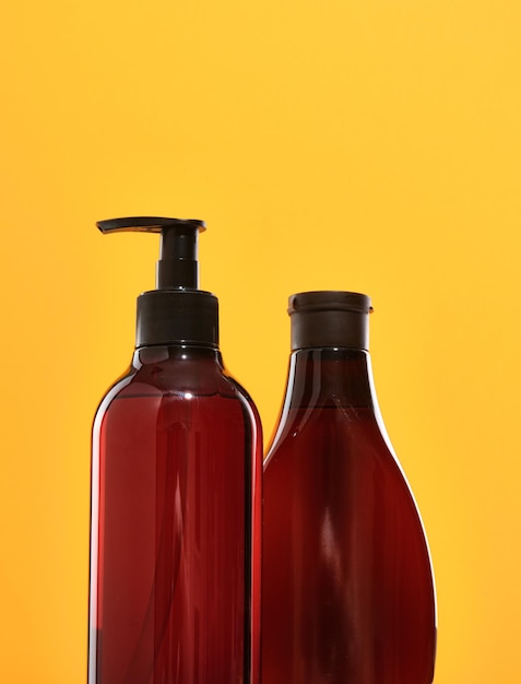 Dispenser en fles van donkerbruine kleur met douchegel en vloeibare zeep