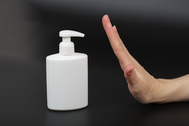 Dispenser with disinfectant and a mask on a black background.Closeup