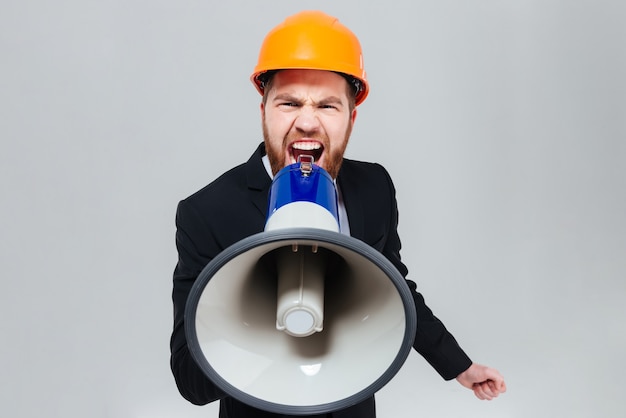 Displeased bearded engineer shouting in megaphone