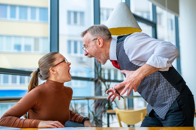 Displeased boss in glasses screaming at woman manager in office